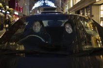 Sonriente pareja conduciendo coche por la noche - foto de stock