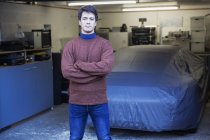 Portrait confident man standing in front of covered car in garage — Stock Photo