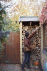 Man reaching for firewood on autumn patio — Stock Photo