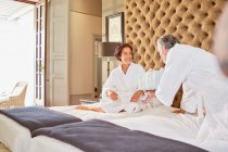 Husband surprising wife with gift on hotel bed — Stock Photo