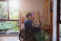 Artista masculino em pintura em cadeira de rodas em estúdio de arte — Fotografia de Stock