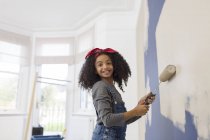 Portrait happy girl painting wall — Stock Photo