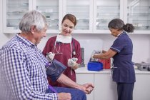 Krankenschwester überprüft Blutdruck eines älteren männlichen Patienten im Untersuchungsraum der Klinik — Stockfoto