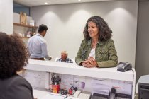 Lächelnde Frau checkt an Klinik-Rezeption ein — Stockfoto