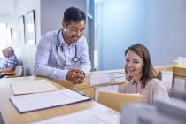 Усміхнений лікар і ресепшн обговорюють медичний запис у клініці — стокове фото