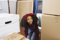 Retrato menina feliz, bonito entre as caixas móveis — Fotografia de Stock