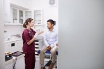 Female doctor talking with male patient in clinic examination room — Stock Photo