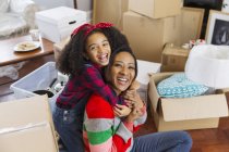 Retrato feliz, mãe entusiasta e filha abraçando entre caixas, casa em movimento — Fotografia de Stock