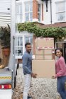 Portrait happy couple moving house, carrying cardboard boxes in driveway — Stock Photo