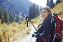 Caminhante feminina com mochila e postes de caminhada viajando na área da montanha — Fotografia de Stock