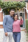 Retrato casal feliz segurando as chaves da casa fora da casa nova — Fotografia de Stock