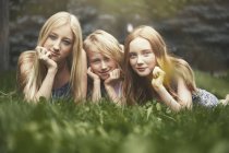 Portrait beautiful sisters laying in grass — Stock Photo