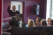 Male conductor leading women singing in music recording studio — Stock Photo
