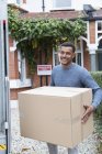 Retrato hombre confiado mudanza casa, llevando caja de cartón - foto de stock
