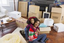 Portrait heureux, mère affectueuse et fille étreignant parmi les boîtes, déménageant maison — Photo de stock