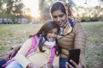 Madre musulmana en hiyab tomando selfie con su hija en el parque de otoño - foto de stock