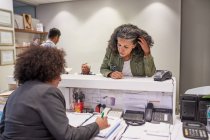 Female patient rescheduling with receptionist in clinic — Stock Photo