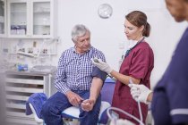 Врач, проверяющий кровяное давление пожилых пациентов в кабинете — стоковое фото