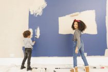 Portrait happy brother and sister painting wall — Stock Photo