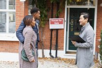 Real estate agent talking with couple outside house for sale — Stock Photo