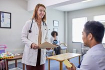 Female doctor talking with male patient in clinic waiting room — Stock Photo