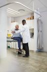 Male doctor examining senior patient in clinic examination room — Stock Photo