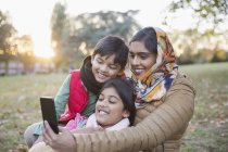 Mãe muçulmana no hijab tomando selfie com telefone câmera no parque de outono — Fotografia de Stock