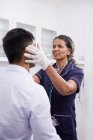 Médecin féminin examinant un patient masculin en salle d'examen clinique — Photo de stock