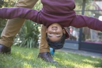 Playful boy hanging upside down — Stock Photo
