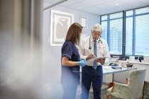 Medico e infermiere con tablet digitale parlare, consulenza in ambulatorio medici ufficio — Foto stock