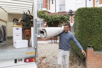 Portrait confident man carrying rug outside moving van, moving house — Stock Photo