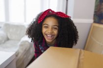 Retrato menina feliz atrás da caixa de papelão, movendo-se para a nova casa — Fotografia de Stock