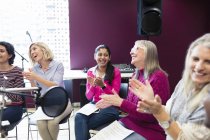 Happy women choir with sheet music singing and clapping in music recording studio — Stock Photo