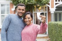 Portrait happy couple with house keys outside new house — Stock Photo