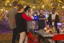Друзі святкують, відкриваючи шампанське на вечірці в саду — стокове фото