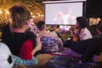 Friends watching movie on projection screen in backyard — Stock Photo