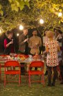 Amici che parlano sotto gli alberi a cena festa in giardino — Foto stock
