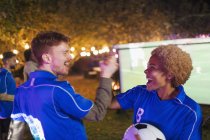 Happy friends cheering, watching soccer match on projection screen in backyard — Stock Photo