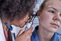 Close up female pediatrician using otoscope, examining ear of girl patient — Stock Photo