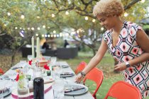 Woman setting table for dinner garden party — Stock Photo