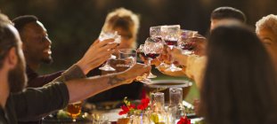 Freunde stoßen Weingläser an, genießen Dinner Gartenparty — Stockfoto