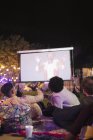 Amigos viendo película en pantalla de proyección en el patio trasero - foto de stock