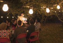 Friends enjoying birthday party with sparkler cake in backyard with fairy lights — Stock Photo