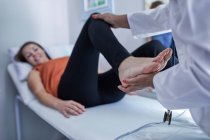 Доктор вивчає ногу пацієнта-жінки в аудиторії — стокове фото