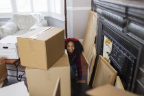 Retrato lindo, chica juguetona entre cajas de cartón, casa móvil - foto de stock