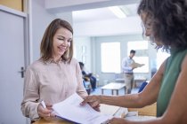 Receptionist helping woman with paperwork at clinic reception — Stock Photo
