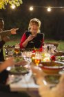 Щаслива жінка сміється, насолоджуючись вечерею в саду вечірка з друзями — стокове фото