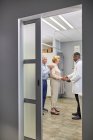 Docteur serrant la main d'un couple de personnes âgées en salle d'examen clinique — Photo de stock
