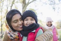 Portrait happy Muslim mother in hijab hugging son in autumn park — Stock Photo