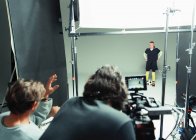 Fotógrafos orientando modelo de jogador de futebol feminino em estúdio durante sessão de fotos — Fotografia de Stock